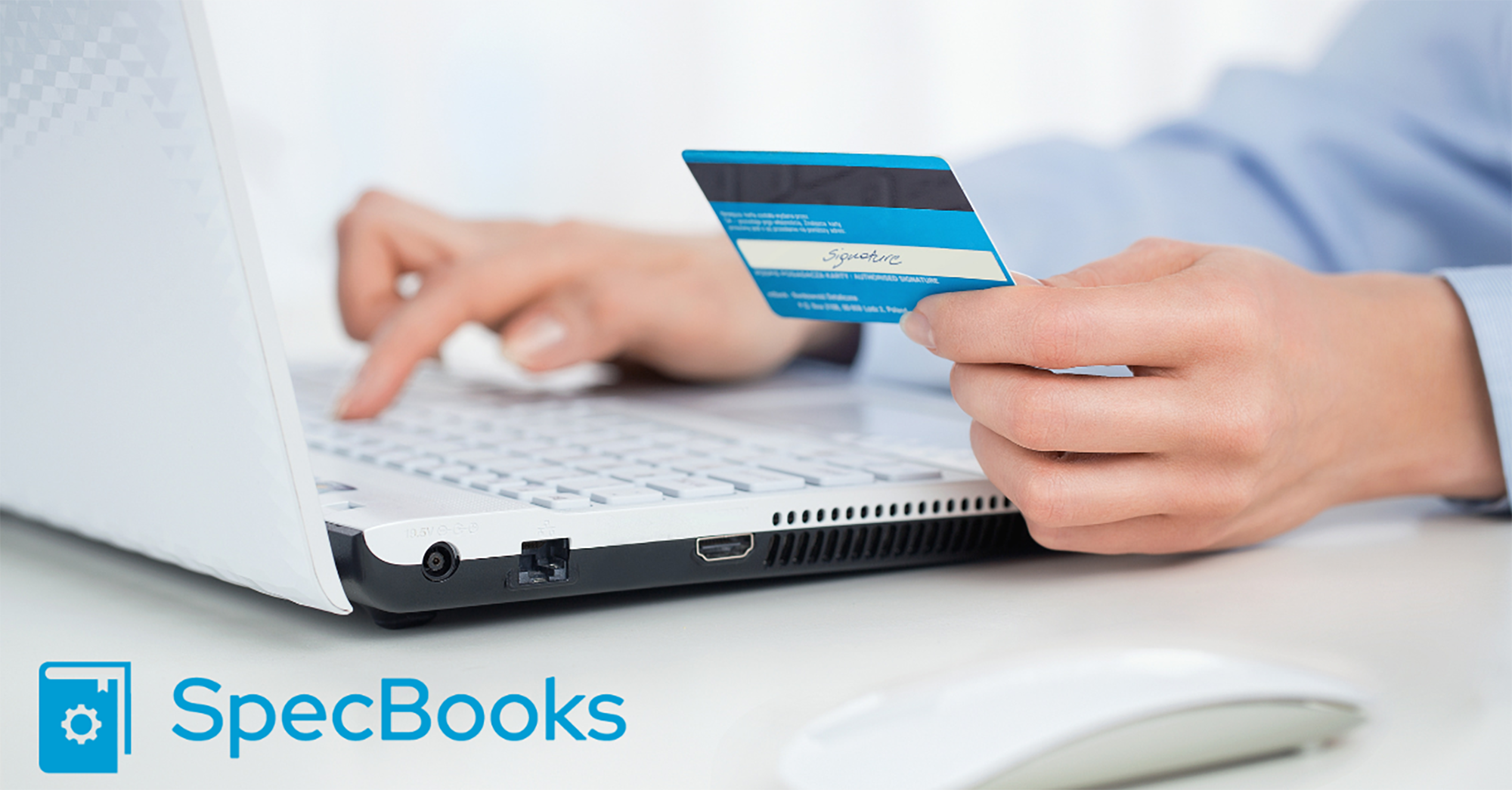 A person in a blue shirt holds their credit card as they type on a white laptop. The SpecBooks logo is in the corner.